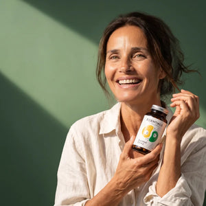 Mujer sonriendo sujetando el bote de DuoWell D3+K2 de Naturadika